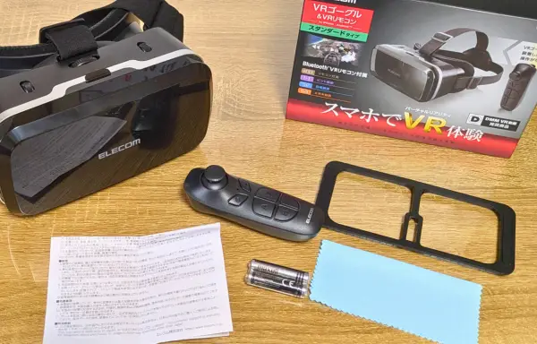 スマホで使えるELECOM製VRゴーグルのセット内容。リモコンやレンズフレーム、説明書などが机に並べられている