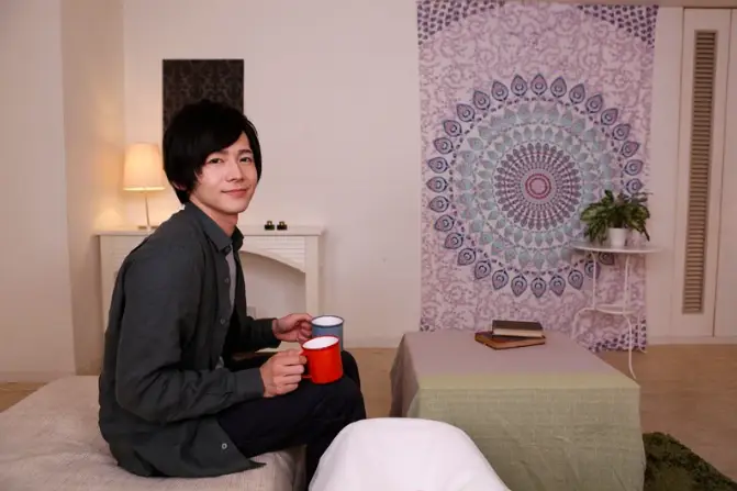 ソファに座って微笑む夏目哉大。カップを手に、穏やかな時間を一緒に過ごしているようなワンシーン♡